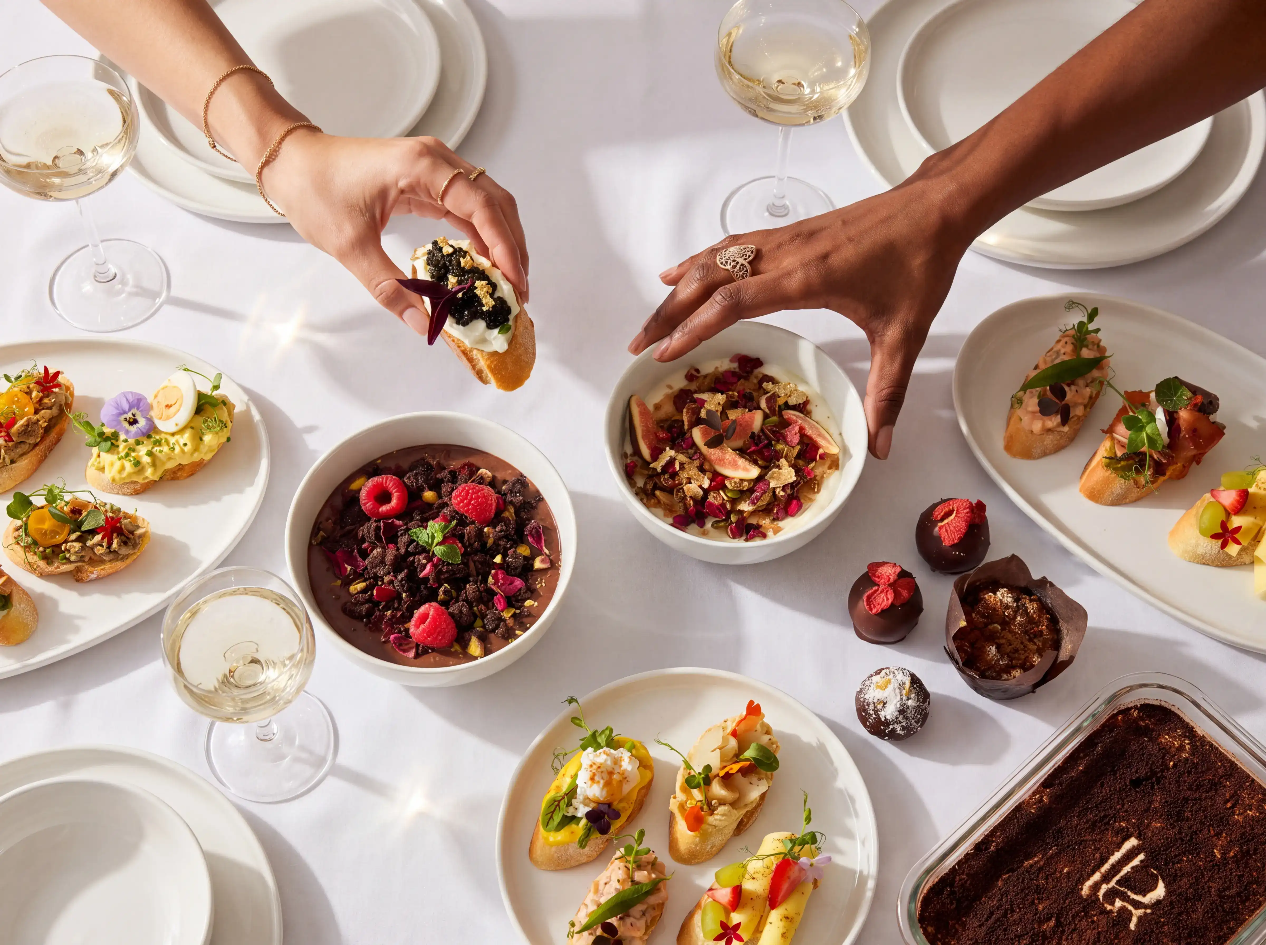 Guests sharing canapes, breakfast bowls, and desserts around an elegant event table.